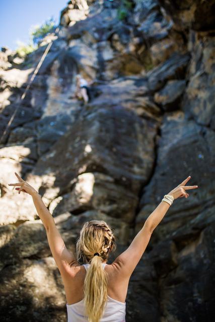 A climber with arms raised at the top of a route